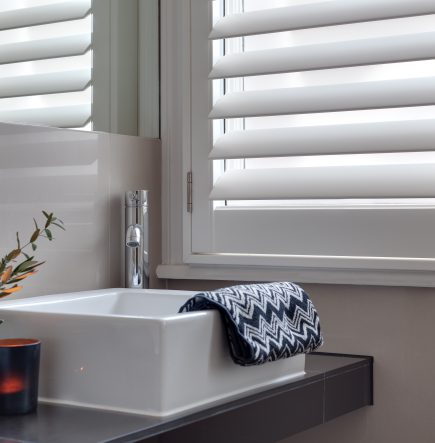 Bathroom detail with Salcombe waterproof shutters and a white sink.